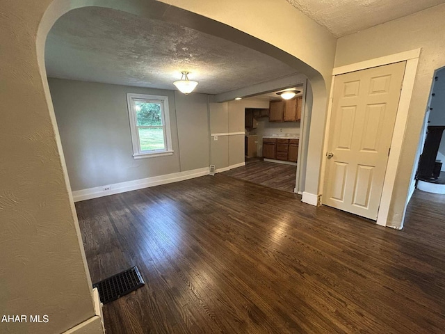 325 Mcfarland Rd, Tyrone, PA 16686 - unfurnished living room featuring arched walkways, a textured ceiling, and dark wood-type flooring