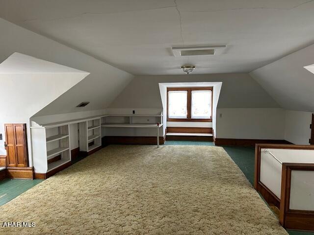 bonus room with vaulted ceiling and dark colored carpet