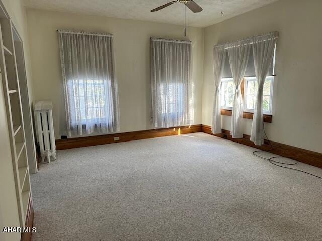 spare room featuring a textured ceiling, ceiling fan, radiator heating unit, and carpet floors