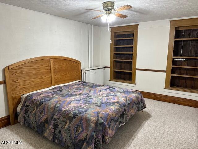 bedroom featuring a textured ceiling, light colored carpet, and ceiling fan