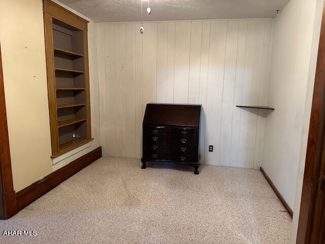 carpeted bedroom with a textured ceiling and wooden walls