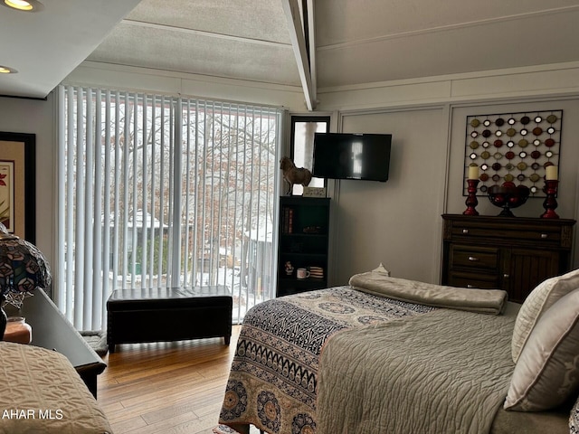 bedroom featuring beam ceiling and light hardwood / wood-style flooring