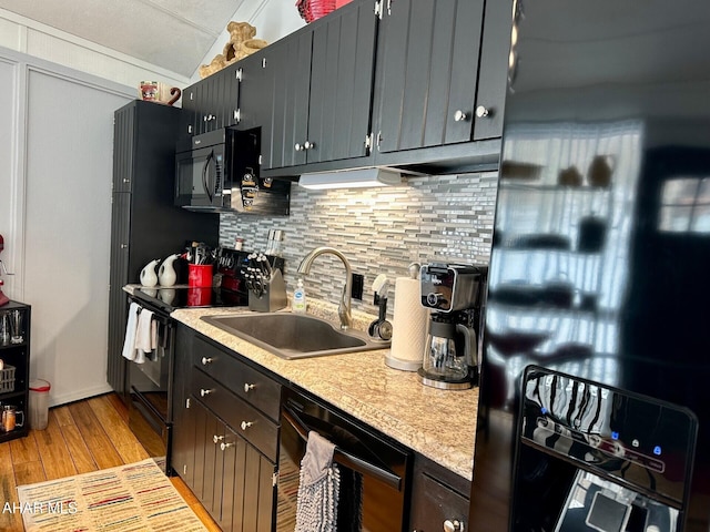 kitchen with light hardwood / wood-style floors, decorative backsplash, beverage cooler, black appliances, and sink