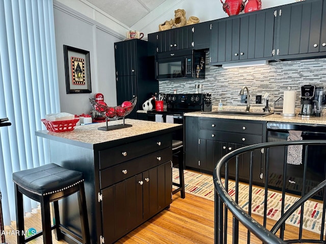 kitchen with a kitchen bar, backsplash, light wood-type flooring, black appliances, and sink