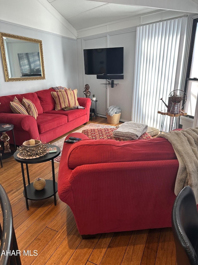 living room with a healthy amount of sunlight, vaulted ceiling, and hardwood / wood-style floors