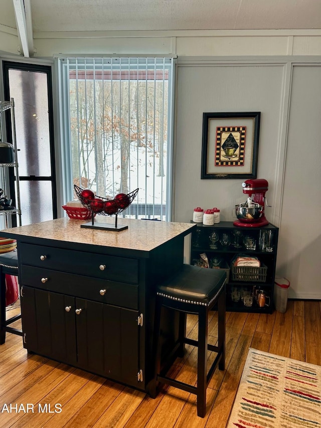 kitchen with a breakfast bar, light hardwood / wood-style flooring, and beamed ceiling