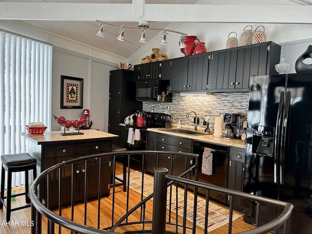 kitchen with tasteful backsplash, a center island, black appliances, sink, and light wood-type flooring