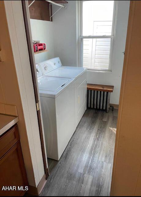 washroom featuring radiator, dark hardwood / wood-style floors, and washing machine and clothes dryer