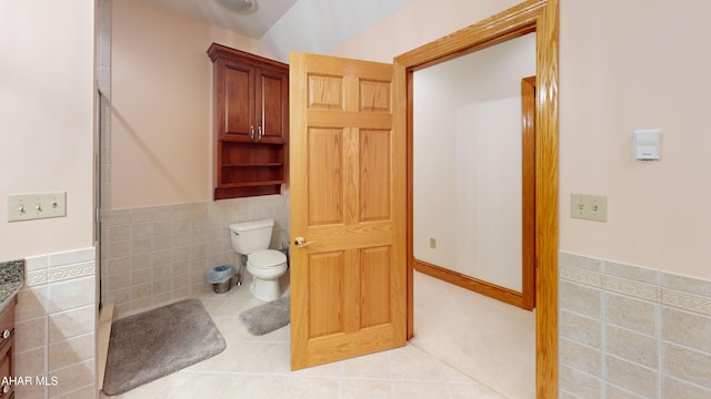 full bath featuring tile walls, vanity, toilet, tile patterned flooring, and a wainscoted wall