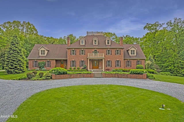 colonial home with a chimney, brick siding, and curved driveway