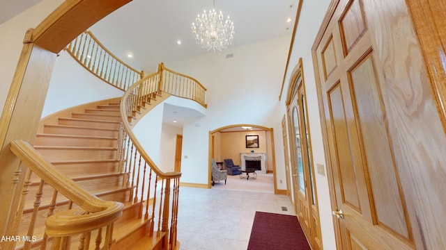 entrance foyer featuring arched walkways, stairway, a high ceiling, a chandelier, and baseboards