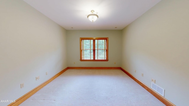 unfurnished room with light colored carpet and baseboards