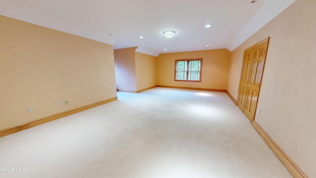 empty room featuring baseboards, lofted ceiling, light carpet, and recessed lighting