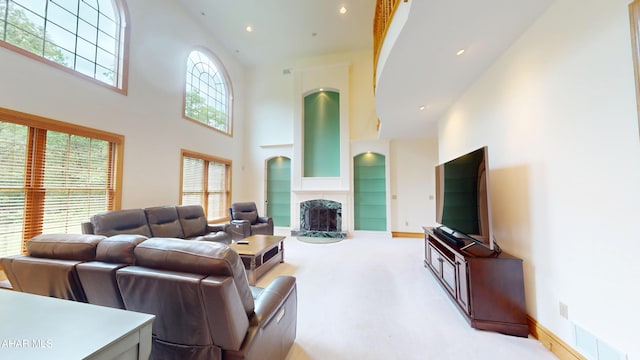 living area with a towering ceiling, a tile fireplace, carpet flooring, and recessed lighting
