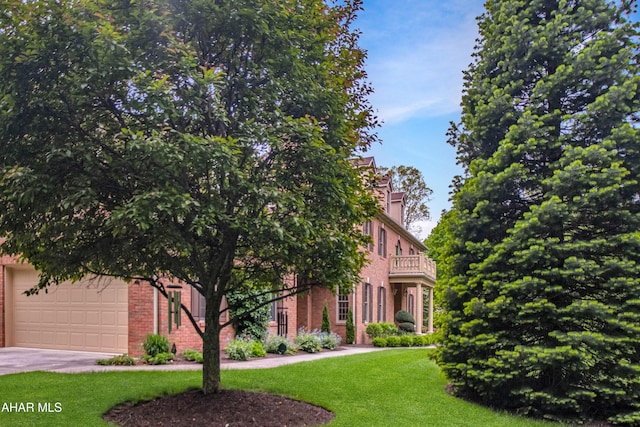 view of front of house featuring a balcony, brick siding, a front yard, concrete driveway, and an attached garage