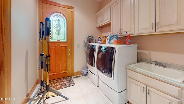 clothes washing area with washer and clothes dryer, cabinet space, light tile patterned flooring, and baseboards