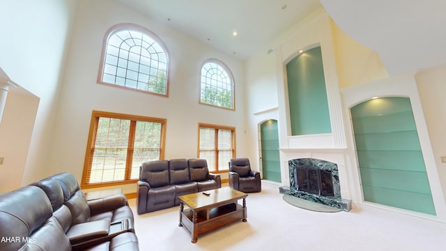 living area with a towering ceiling, a high end fireplace, built in shelves, arched walkways, and baseboards