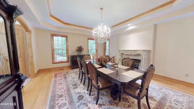 dining room featuring a tray ceiling, a chandelier, light wood-style flooring, arched walkways, and recessed lighting