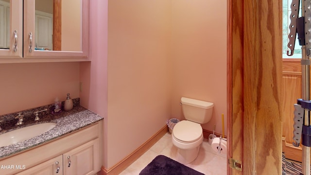 bathroom with toilet, vanity, tile patterned flooring, and baseboards
