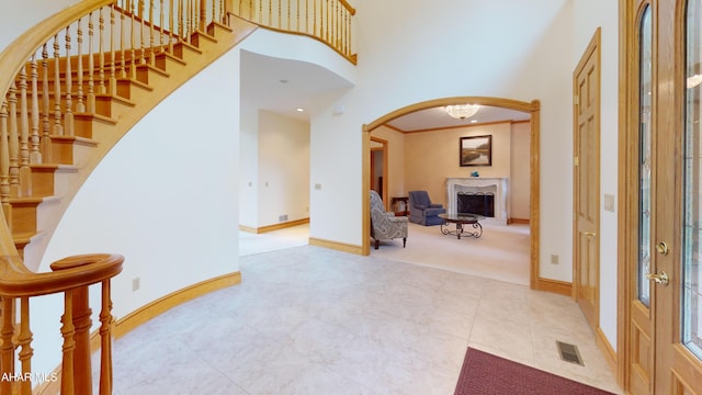 carpeted foyer entrance featuring arched walkways, baseboards, stairs, a towering ceiling, and tile patterned floors