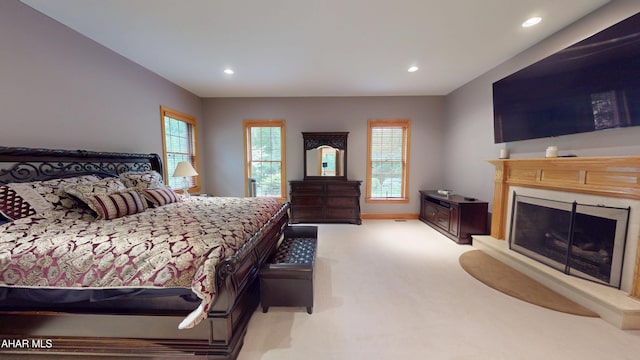 bedroom featuring light carpet, a fireplace with raised hearth, recessed lighting, and baseboards