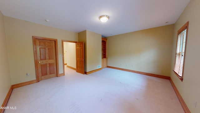 unfurnished room with baseboards and light carpet