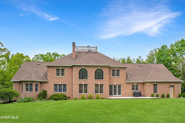 rear view of property with a chimney, a patio area, and a lawn