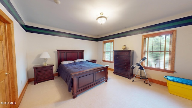 bedroom with light colored carpet and baseboards
