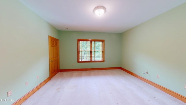 unfurnished room with baseboards and light colored carpet