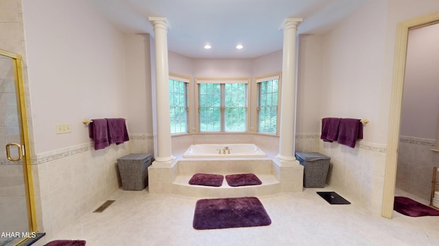 bathroom featuring ornate columns, tile walls, a shower stall, wainscoting, and tile patterned flooring