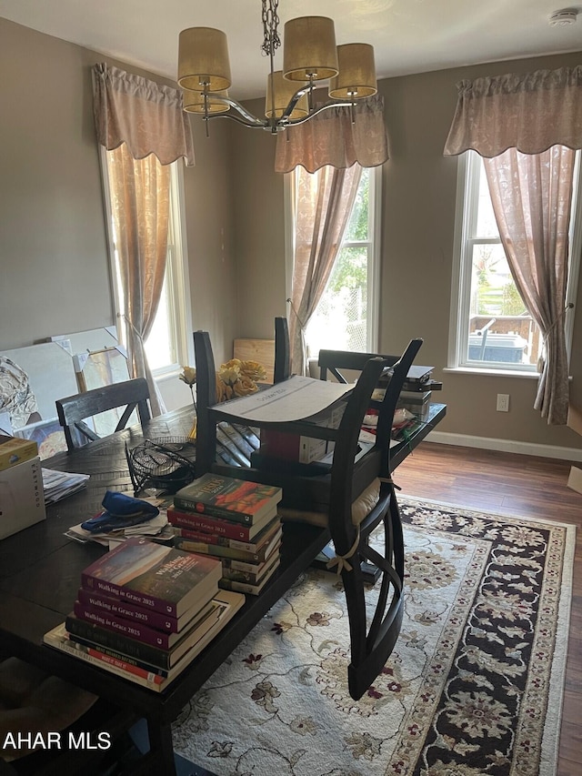 dining space with hardwood / wood-style floors and a notable chandelier