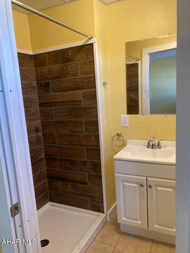 bathroom with tiled shower, vanity, and tile patterned floors