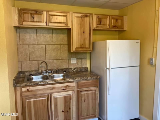 kitchen featuring a paneled ceiling, white fridge, sink, and tasteful backsplash