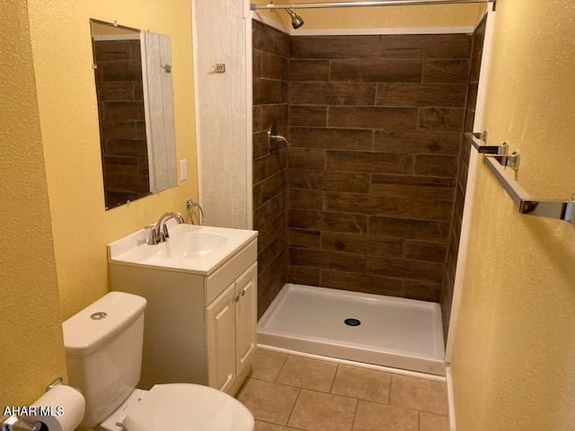 bathroom with tile patterned floors, toilet, a tile shower, and vanity