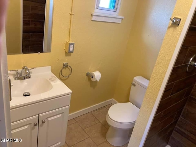 bathroom with tile patterned flooring, vanity, tiled shower, and toilet