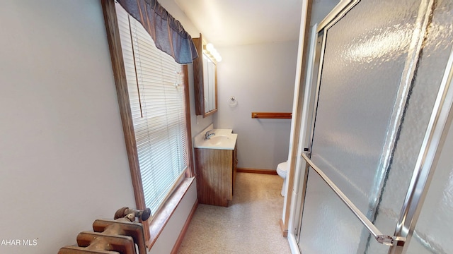 bathroom featuring vanity, a shower with shower door, and toilet