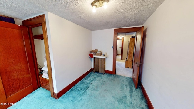 hall with light colored carpet and a textured ceiling