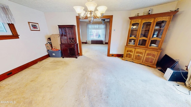 unfurnished room featuring an inviting chandelier, light carpet, and a textured ceiling