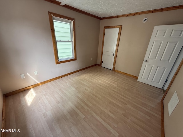 unfurnished bedroom with light wood-style floors, baseboards, a textured ceiling, and crown molding