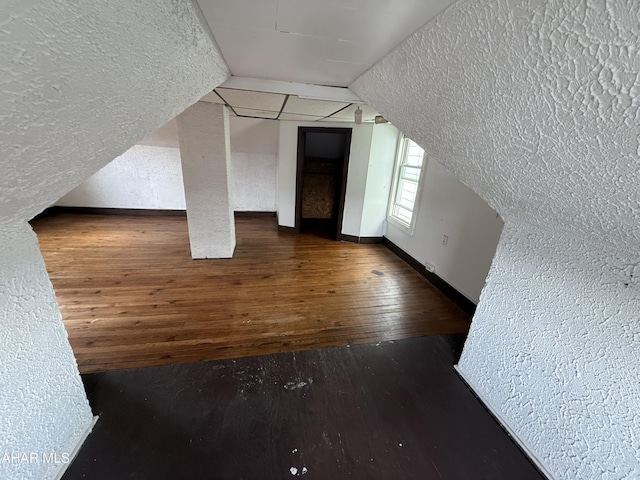 bonus room with a textured wall, hardwood / wood-style floors, baseboards, and a textured ceiling