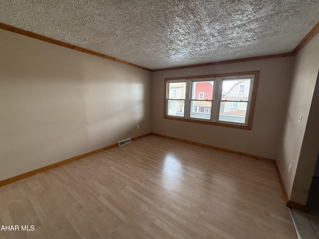 unfurnished room with crown molding, light wood-type flooring, baseboards, and a textured ceiling