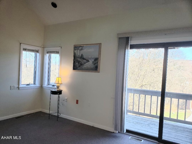 interior space with vaulted ceiling, visible vents, baseboards, and dark colored carpet