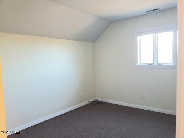 bonus room featuring dark colored carpet and lofted ceiling