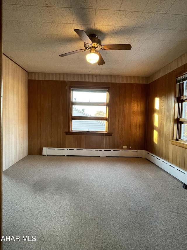 carpeted spare room featuring ceiling fan and wood walls