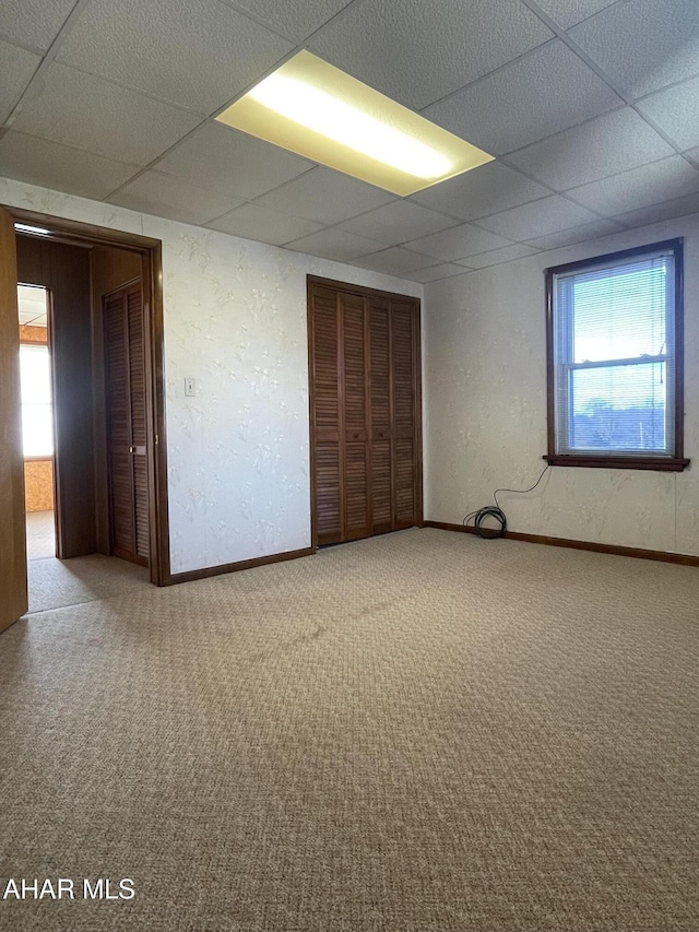 carpeted empty room featuring a paneled ceiling