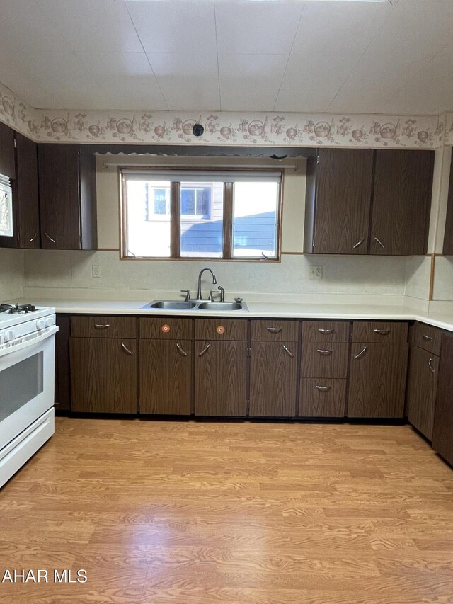 kitchen with plenty of natural light, sink, white appliances, and light wood-type flooring