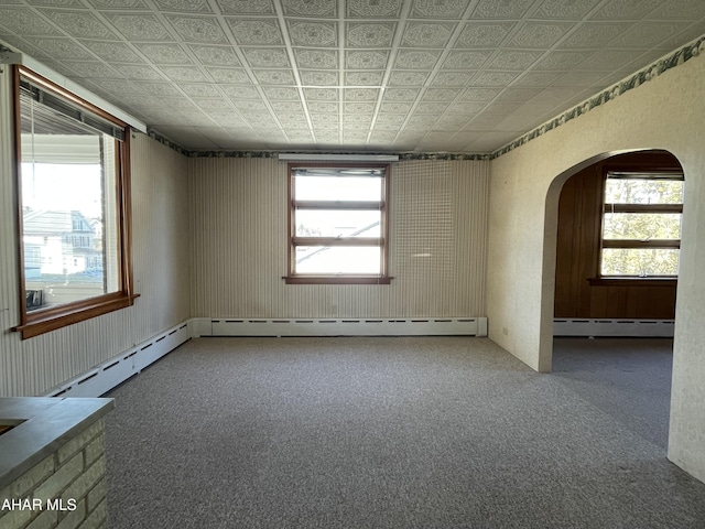 unfurnished room with a healthy amount of sunlight and a baseboard heating unit