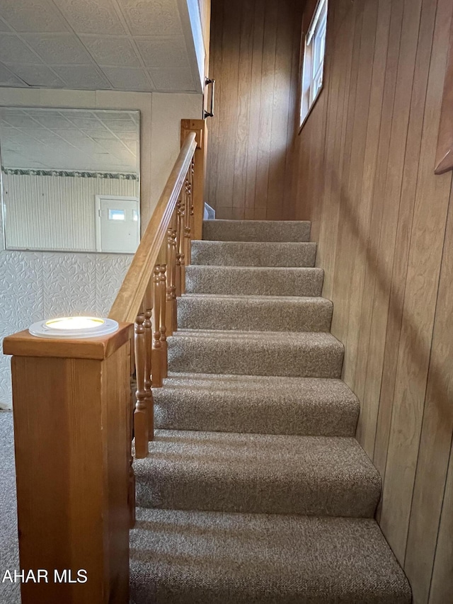 stairway featuring wooden walls