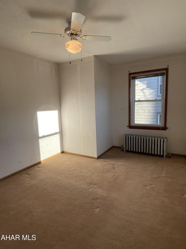 unfurnished room with carpet flooring, ceiling fan, ornamental molding, and radiator