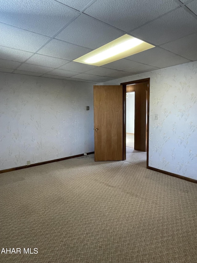 spare room with a paneled ceiling and light colored carpet